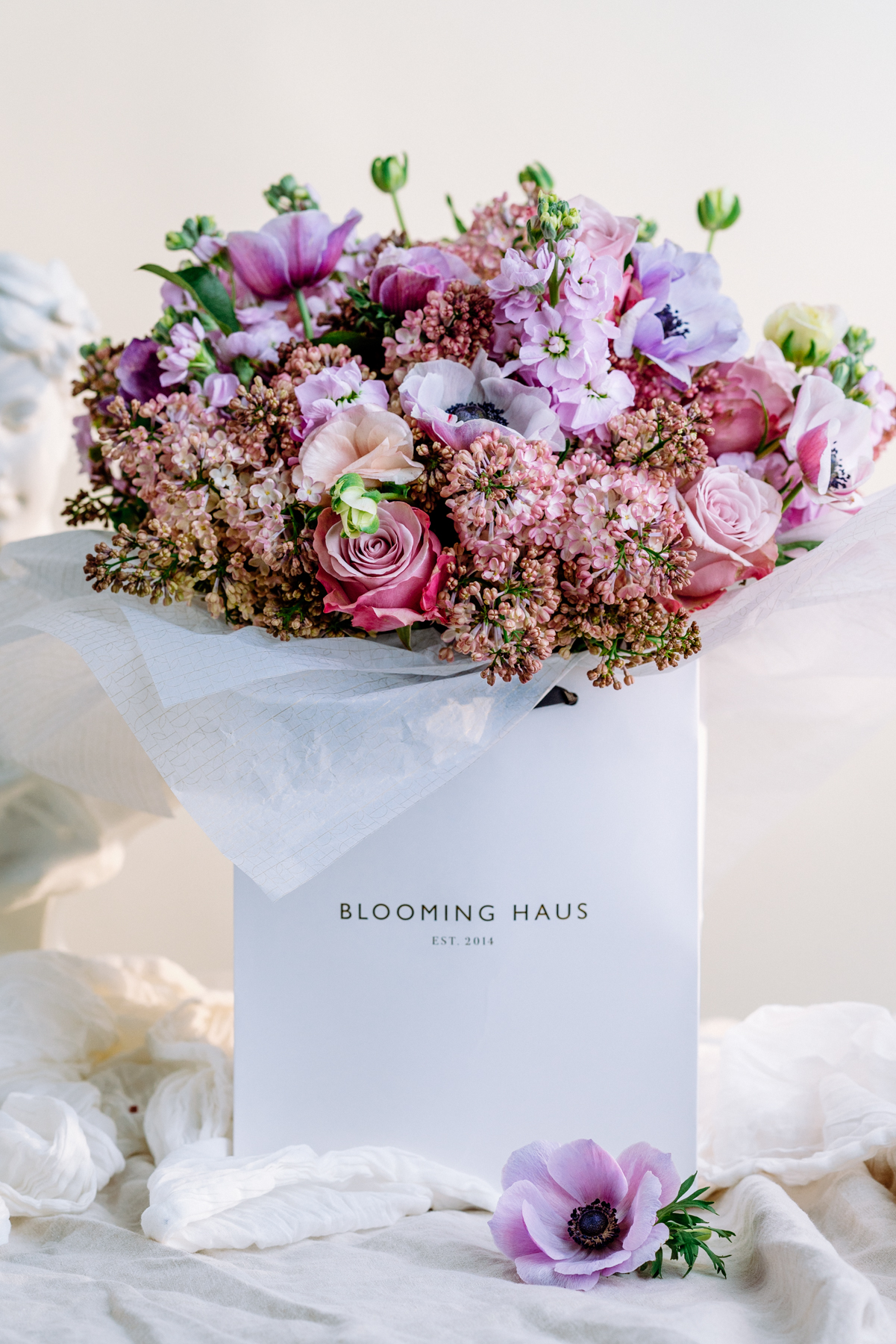 Anemone, purple roses, pink lilacs and purple stocks round bouquet by blooming haus
