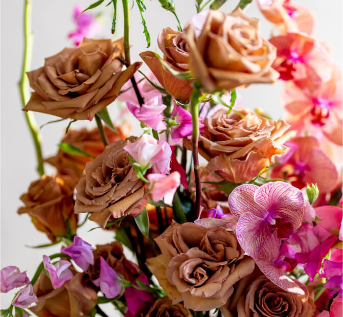 A vibrant bouquet featuring brown roses and pink orchids surrounded by delicate pink flowers, this luxury flower arrangement showcases a mix of textures and colors. The soft petals stand out against a light background, creating an elegant and lively composition crafted by an expert florist.