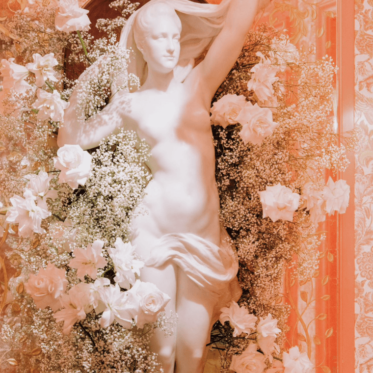 A statue of a naked woman decorated with white flowers