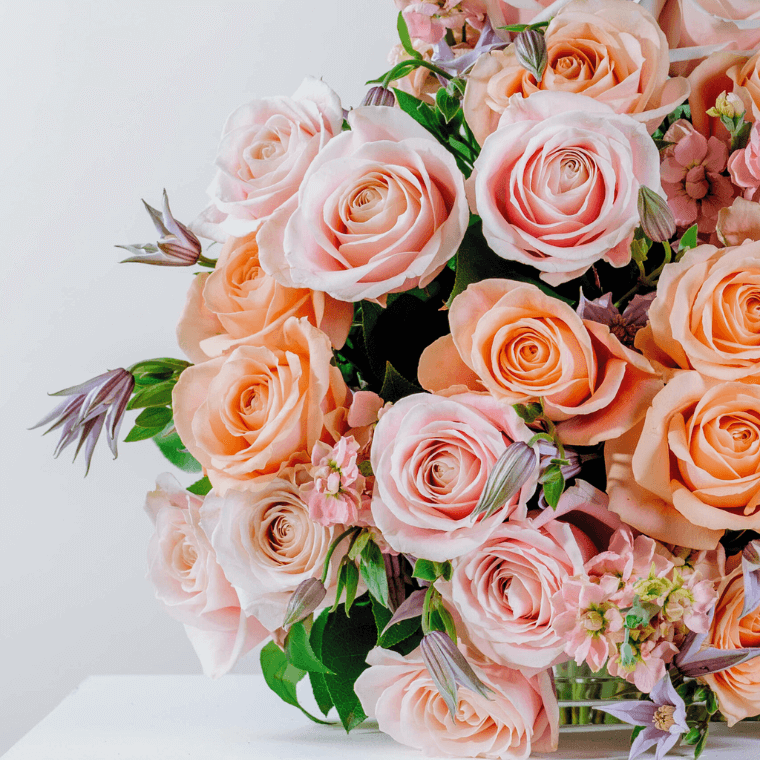 A bouquet of peach and blush roses, clematis, and herbs