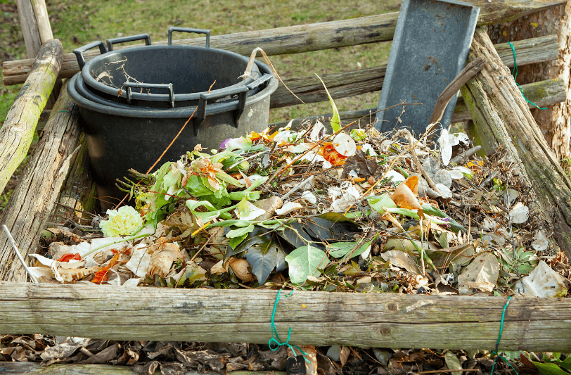 A compost heap with a wooden surround and a compost bin