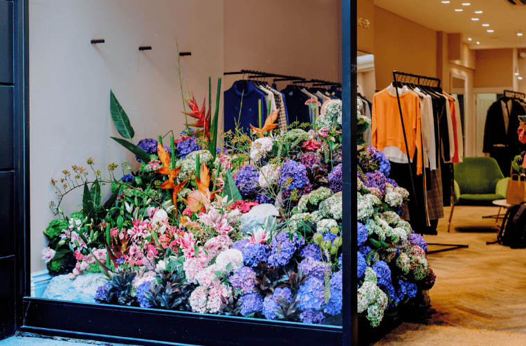 The window of me + em store with a large floral display in blue, pink, orange, and green