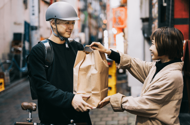 A male bicycle courier handing over a package to a woman