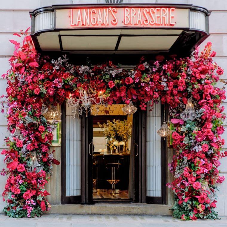 The entrance of langan's brasserie decorated with dark pink flowers from blooming haus