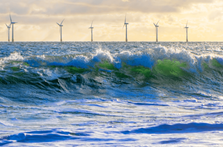 Waves with wind turbines in the background