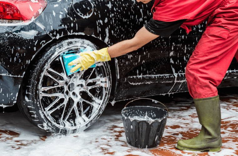 A man washing a black car with soapy water