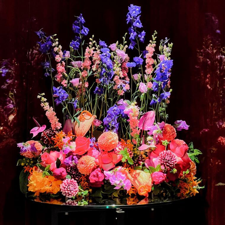 A table display by blooming haus containing purple, pink, and orange flowers