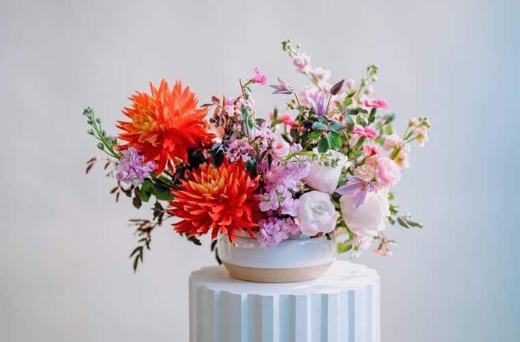 A table display by blooming haus including pink, lilac, and orange blooms