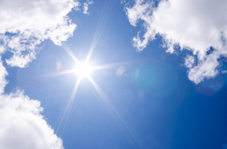 Sun shining in a blue sky with some light cloud