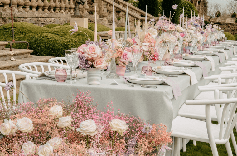 A long outdoor table at euridge manor decorated with pink, lilac, and cream flowers
