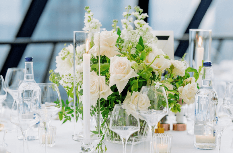 A white and cream floral table setting with glasses and candles