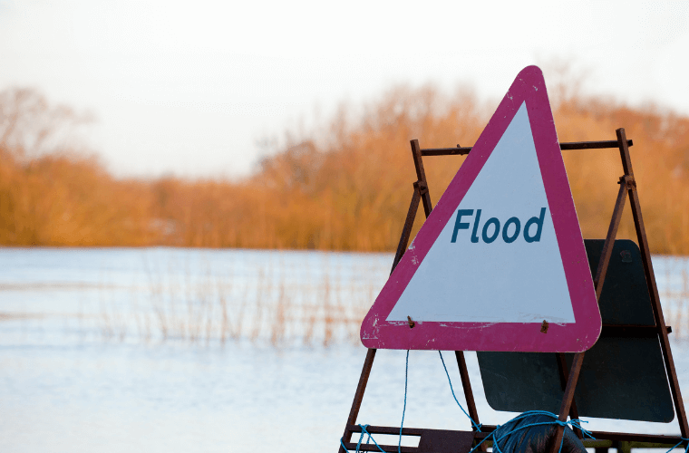 A flood warning sign with a flooded field