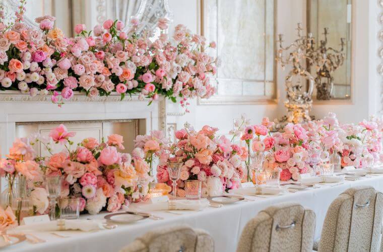 Floral table settings and flowers on a fireplace including pink roses