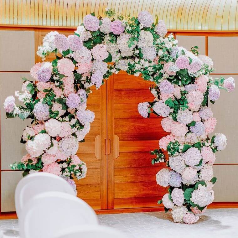 A wedding arch across a wooden door with pastel pink, purple and white flowers