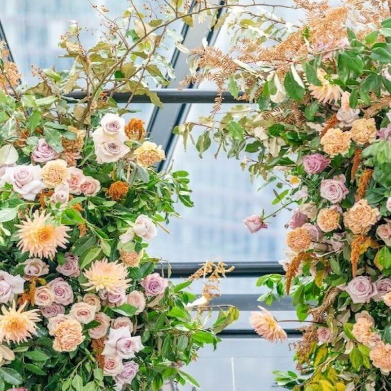 Flower arch with pastel coloured blooms including roses and dahlia