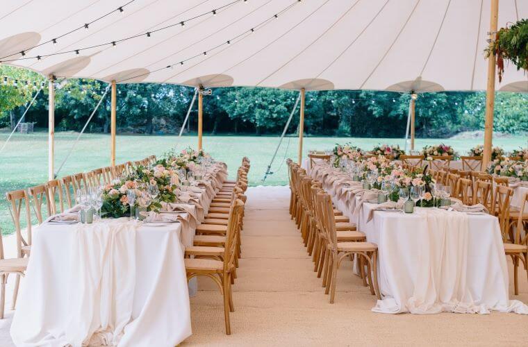 A marquee wedding venue with two long tables laid out for the celebrations