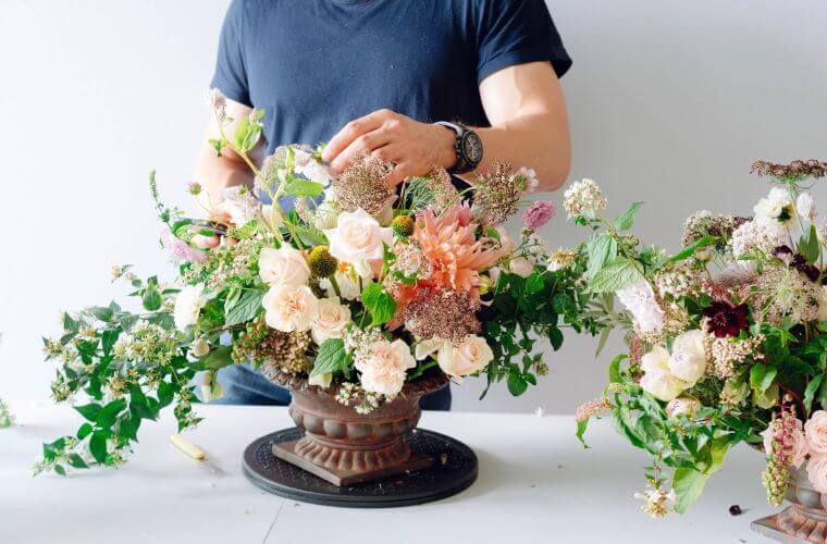 A florist creating a display from pastel coloured flowers including roses and dahlias