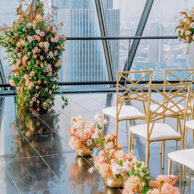 Wedding ceremony set up with chairs and peach and pink flowers looking out over london