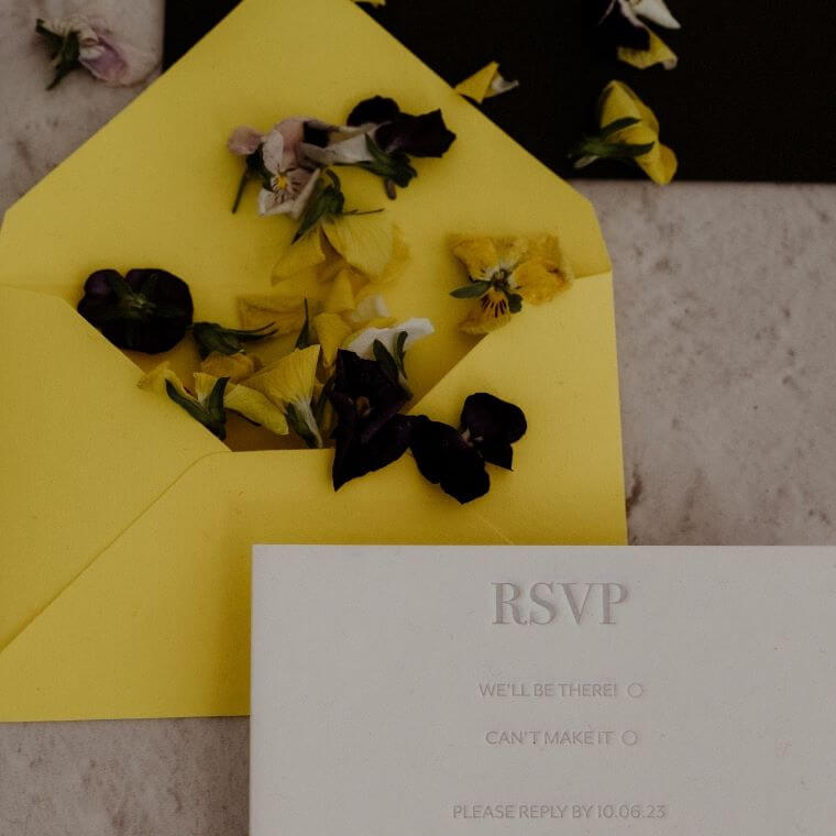 A wedding invitation with a yellow envelope and small scattered flowers