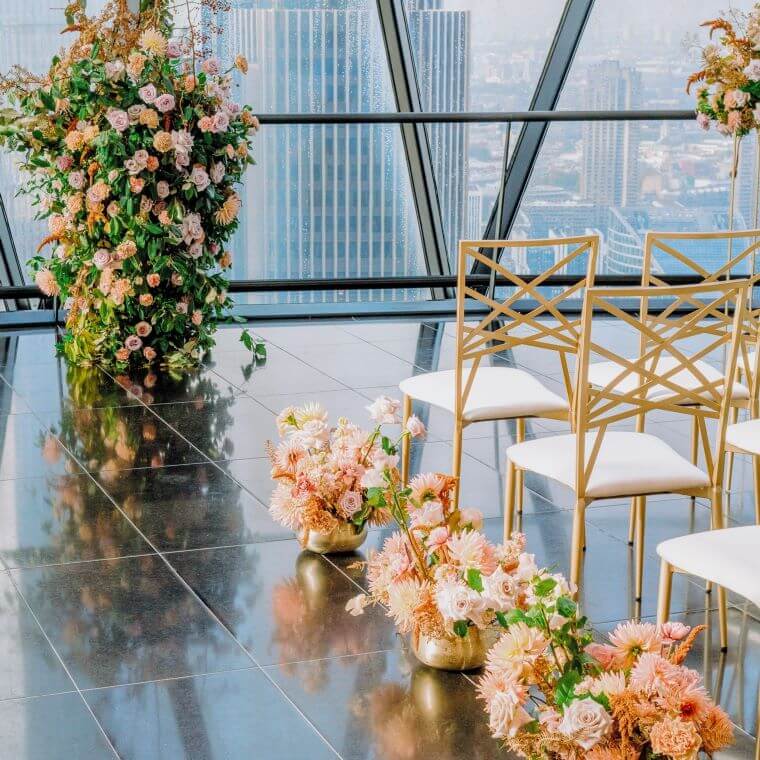 Pastel coloured flowers in vases used as decor for the end of seat rows at a wedding