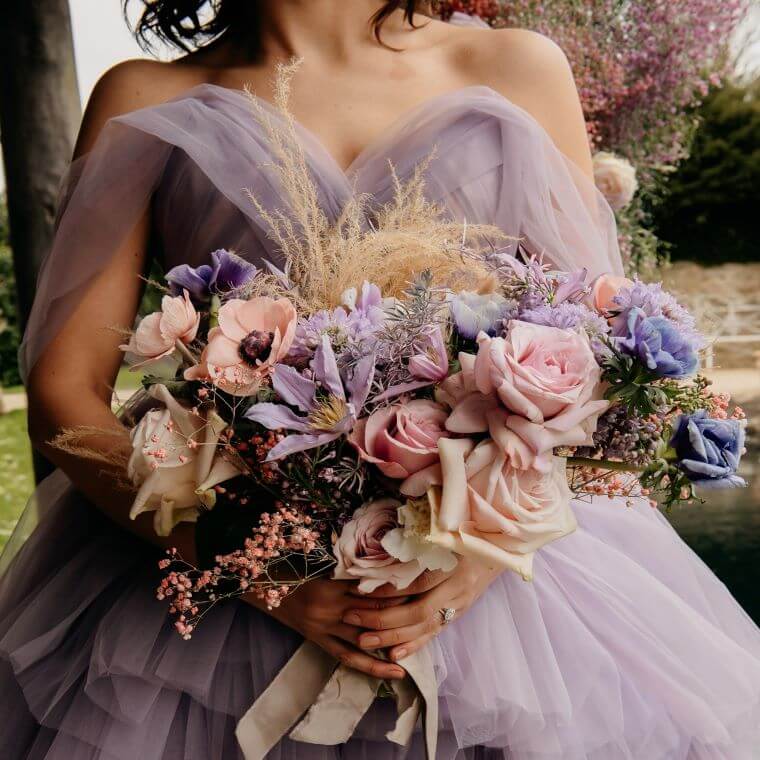 A bride holding a large bouquet of pastel coloured flowers