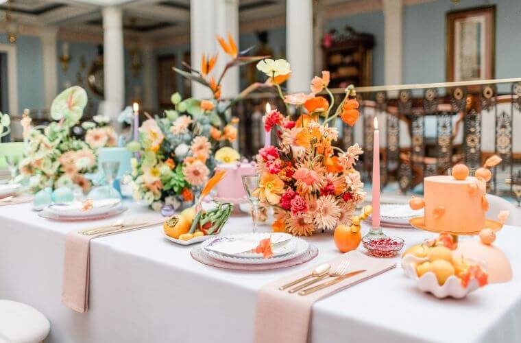 A wedding table with bright coloured orange and gold floral centrepieces