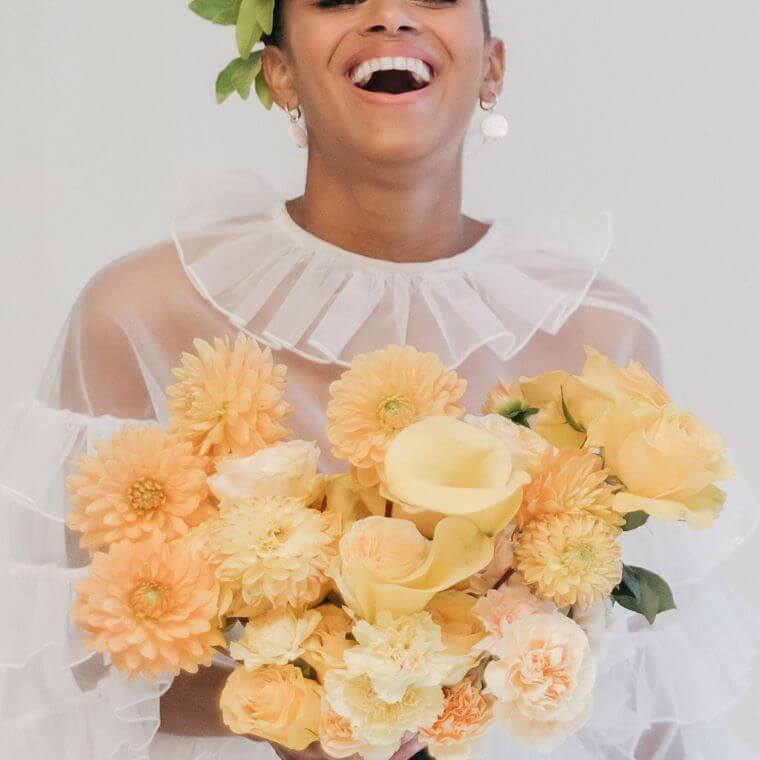 A bride holding a bouquet of blooms in shades of gold and yellow