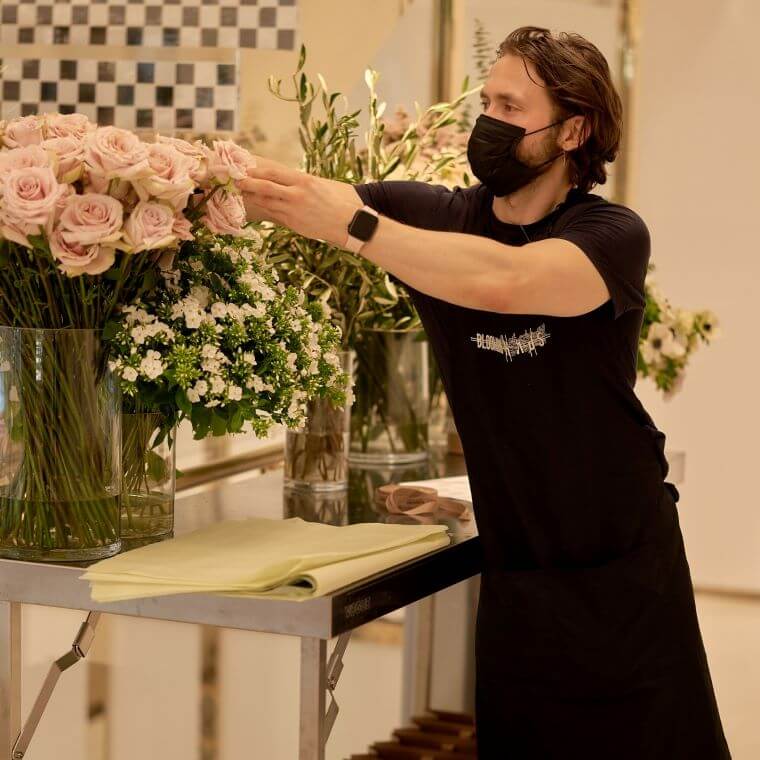 Michal from blooming haus choosing from a vase of pink roses