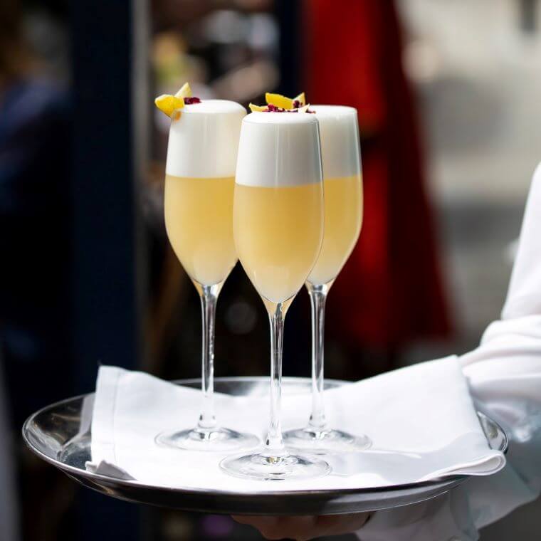 Three orange and white cocktails on a tray