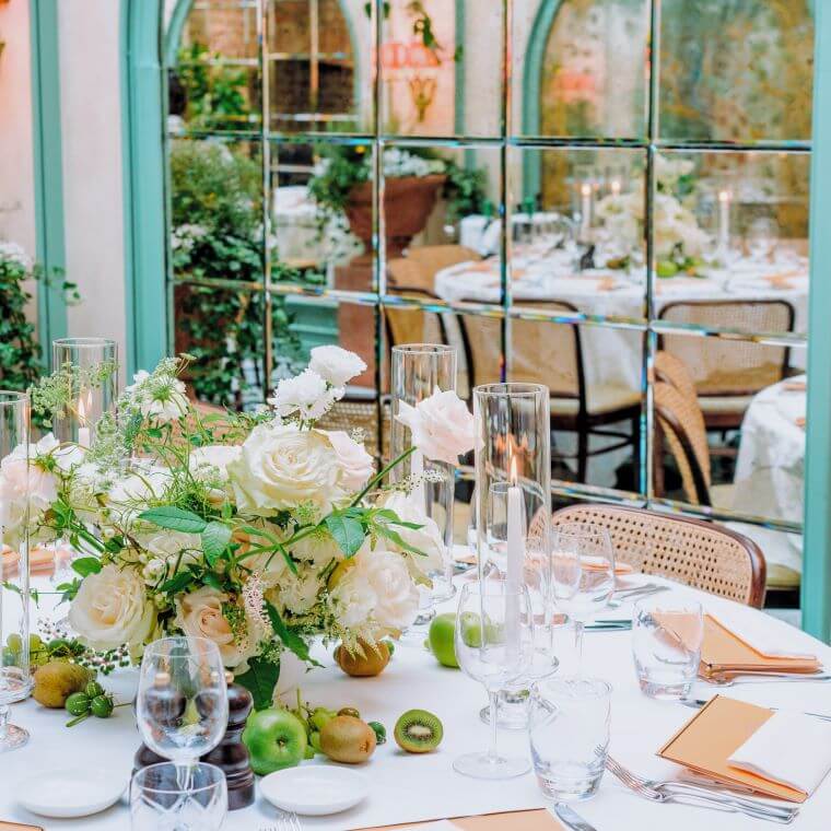 A table set with a floral centrepiece at daphne's with its refection in the window