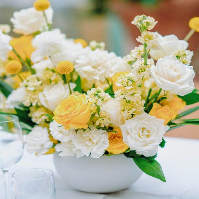 A floral display with yellow and white roses and carnations