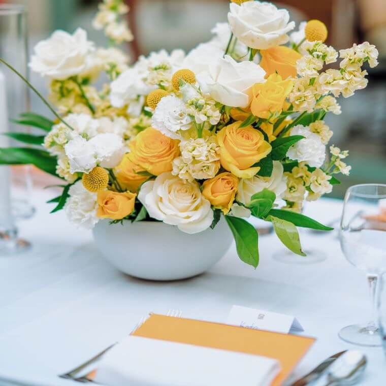 Yellow and white floral display next to a place setting