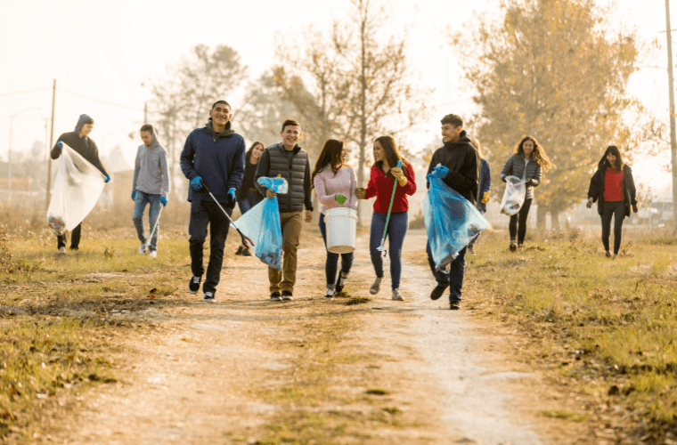 A group of young people in a park wearing gloves and carrying bags to collect rubbish