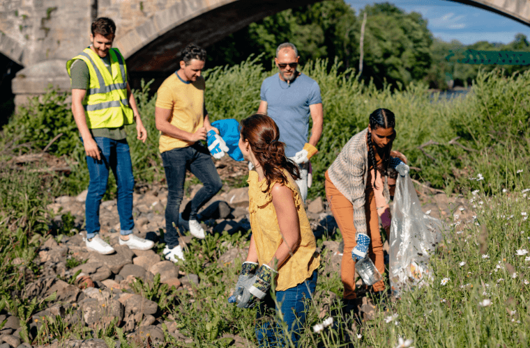 Three men and two women clearing rubbish on an area of grassland