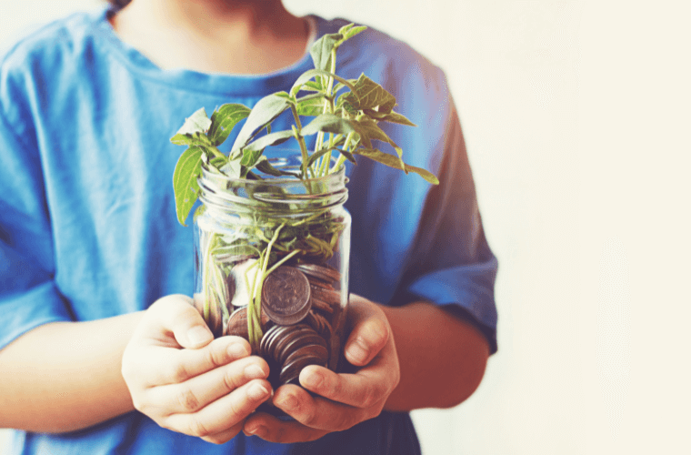 A man holding a jar containing money and plant life