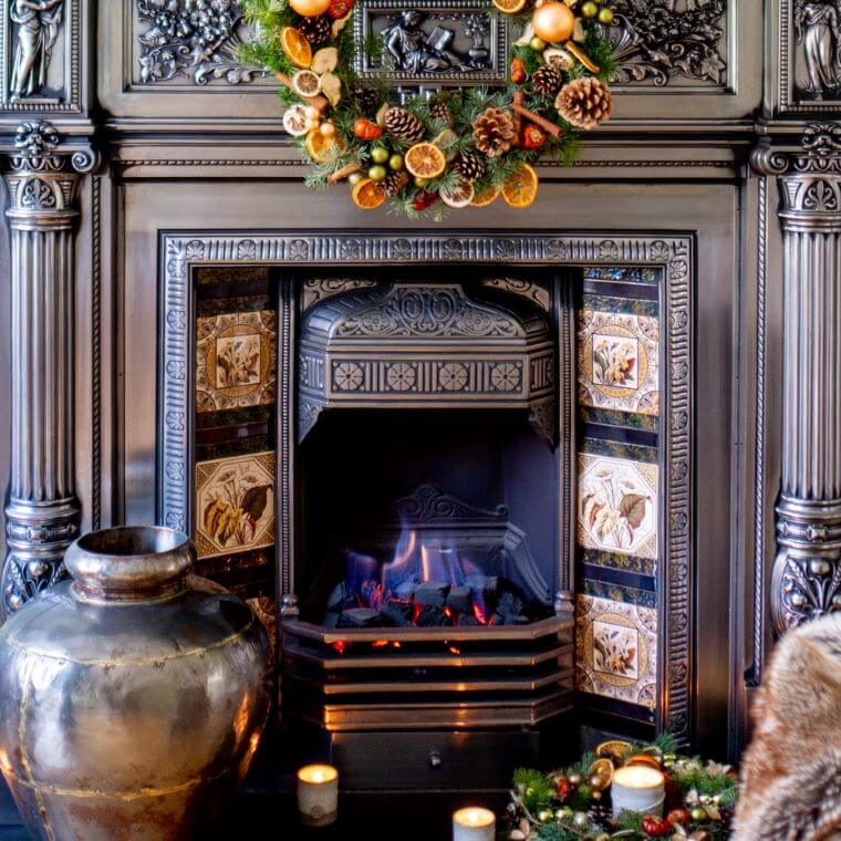 A fireplace with wreaths on the ledge and the hearth