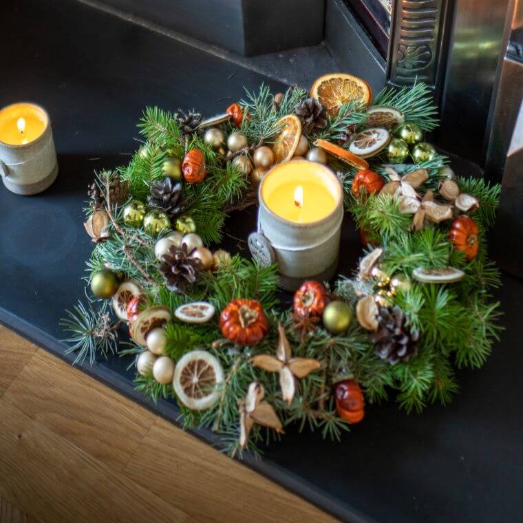 Autumn wreath on a ledge with one candle in the middle of it and one next to it