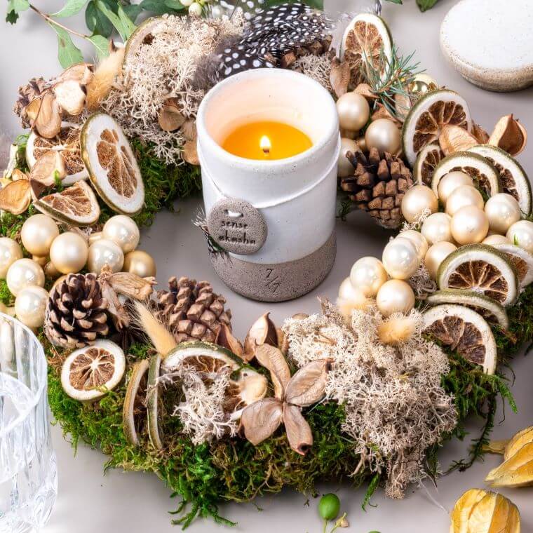 A wreath with weather cones and dried fruit and a candle standing in the middle