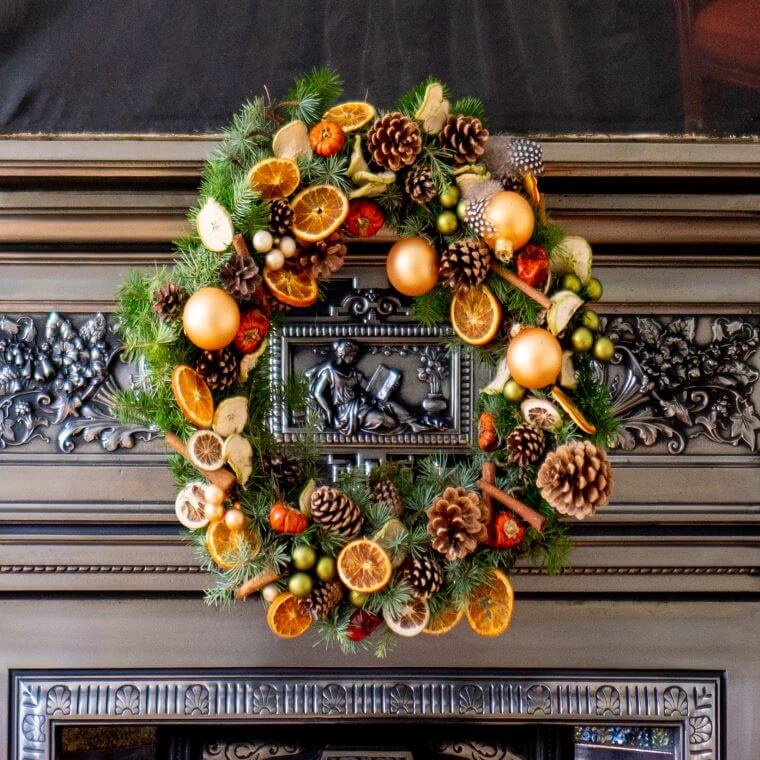 A winter wreath with slices of orange, weather cones, and baubles
